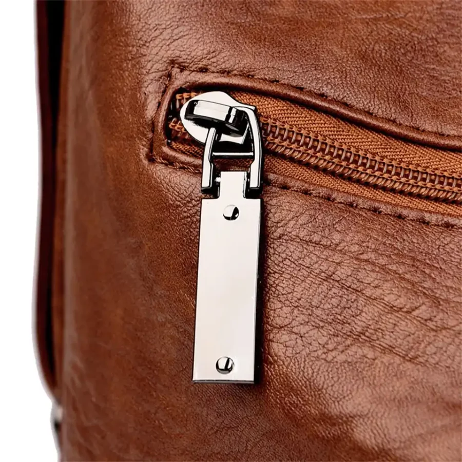 Detaljbild på brun handväska med glänsande metall-dragkedja. Robust design och elegant finish som kombinerar stil och funktion.