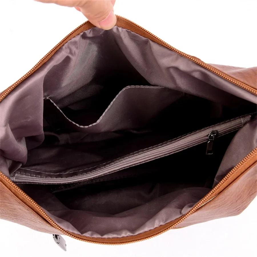 Insidan av brun handväska med flera fack och dragkedja. Rymlig och organiserad för att hålla mobil, plånbok och tillbehör i ordning.